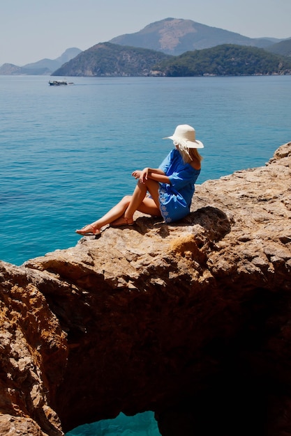 Mujer joven disfrutando de vacaciones en la roca con vista de lujo caminando mostrando emoción en el mar azul