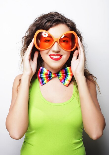 Foto una mujer joven y divertida con grandes gafas de sol naranjas.