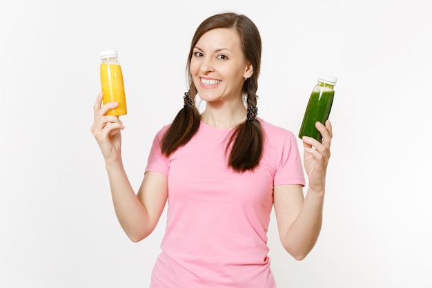 Mujer joven divertida que sostiene batidos de desintoxicación verdes, amarillos en botellas aisladas sobre fondo blanco. Nutrición adecuada, bebida vegetariana, estilo de vida saludable, concepto de dieta. Copie el espacio para publicidad.