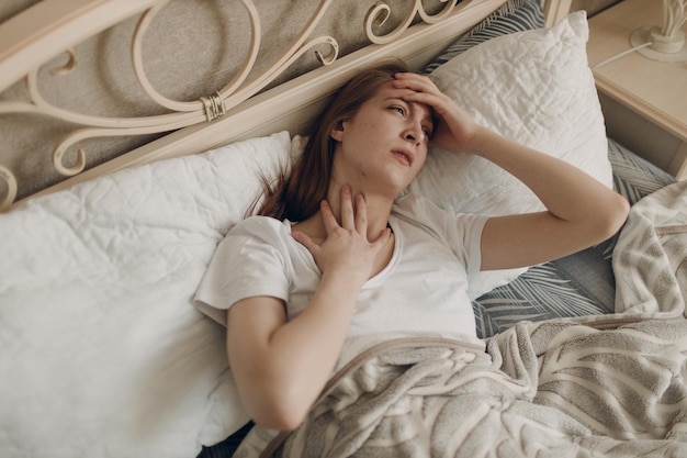 mujer joven, con, dolor de cabeza, gripe, enfermo, enfermedad, frío, en casa, interior, mentira en cama