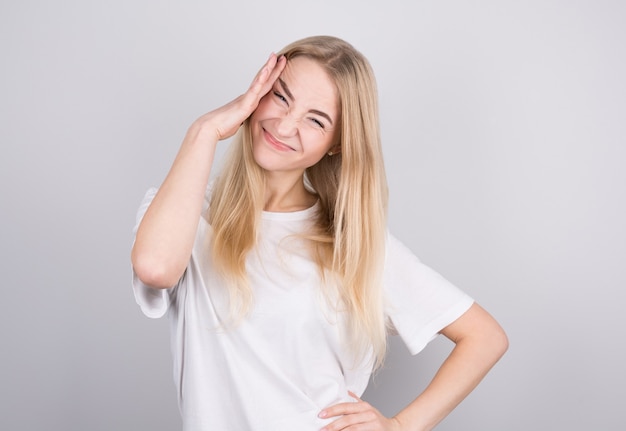 Mujer joven con dolor de cabeza sostiene sus sienes con las manos. Concepto de salud, migraña y dolor de cabeza.