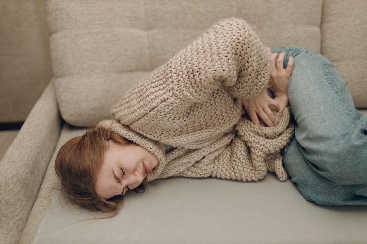 Foto mujer joven con dolor de estómago dolor abdominal acostada en el sofá