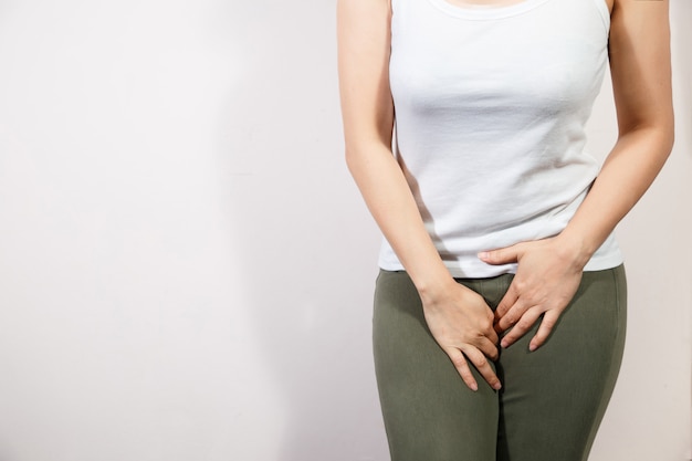 Mujer joven con dolor de estómago doloroso con las manos sosteniendo presionando su entrepierna parte inferior del abdomen.
