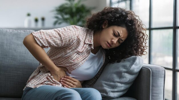 Foto mujer joven con dolor de estómago tendida en el sofá