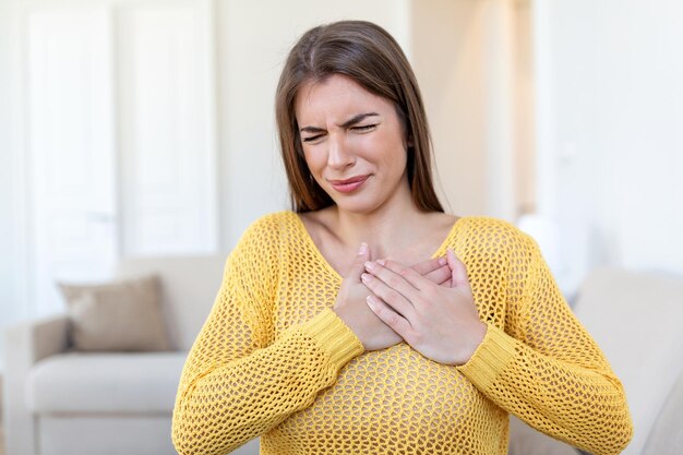 Foto mujer joven con dolor en el pecho dolor agudo posible ataque al corazón efecto del estrés y concepto de estilo de vida no saludable