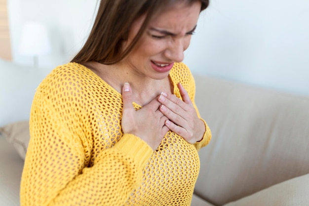 Mujer joven con dolor de pecho Dolor agudo posible ataque al corazón Efecto del estrés y el concepto de estilo de vida poco saludable