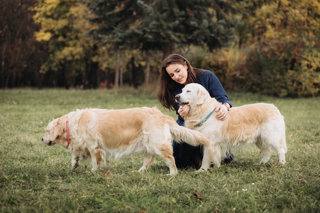 Mujer joven con dos golden retrievers en un hermoso parque de otoño