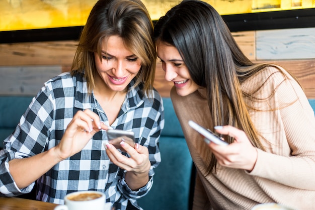 Mujer joven dos que usa smartphone en café