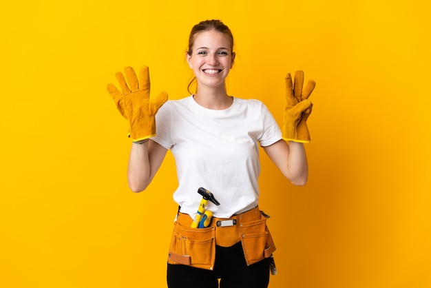 Mujer joven electricista aislada en amarillo contando ocho con los dedos