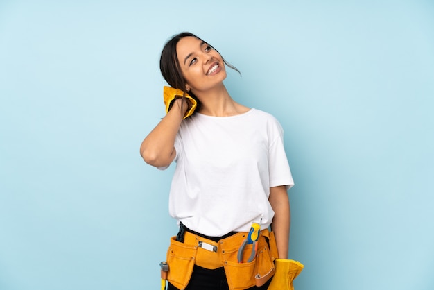 Mujer joven electricista en pared azul pensando una idea