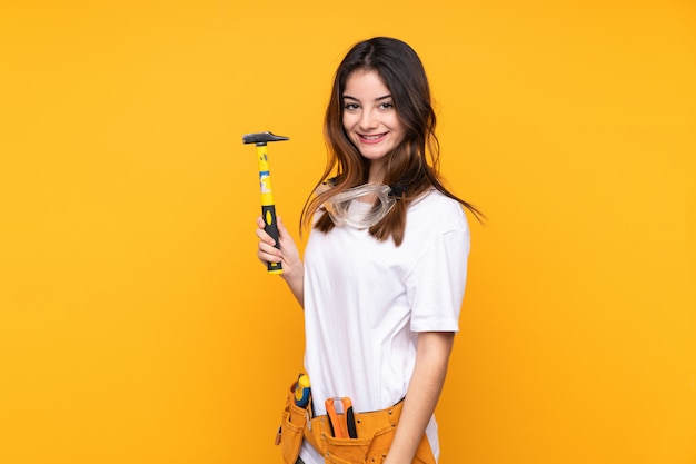 Mujer joven electricista sobre aislado en pared amarilla