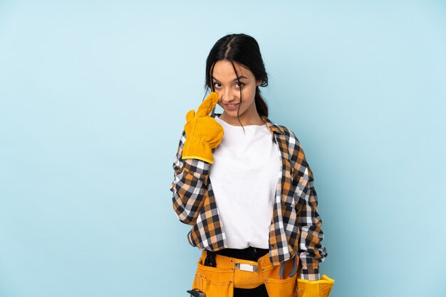 Mujer joven electricista sobre pared aislada