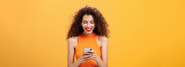 Foto mujer joven elegante y atractiva con peinado rizado anillo de nariz y lápiz labial rojo recogiendo canciones escribiendo