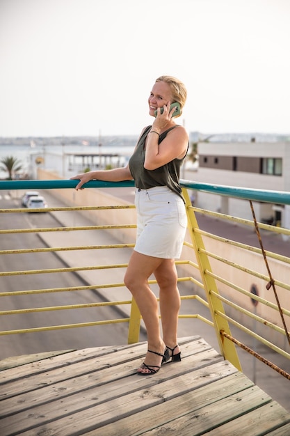 Una mujer joven y elegante se comunica en un teléfono inteligente en una calle de la ciudad