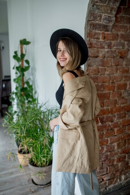 Mujer joven elegante con sombrero y ropa en una casa