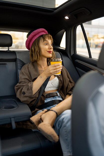 Foto mujer joven y elegante con una taza de café en el coche