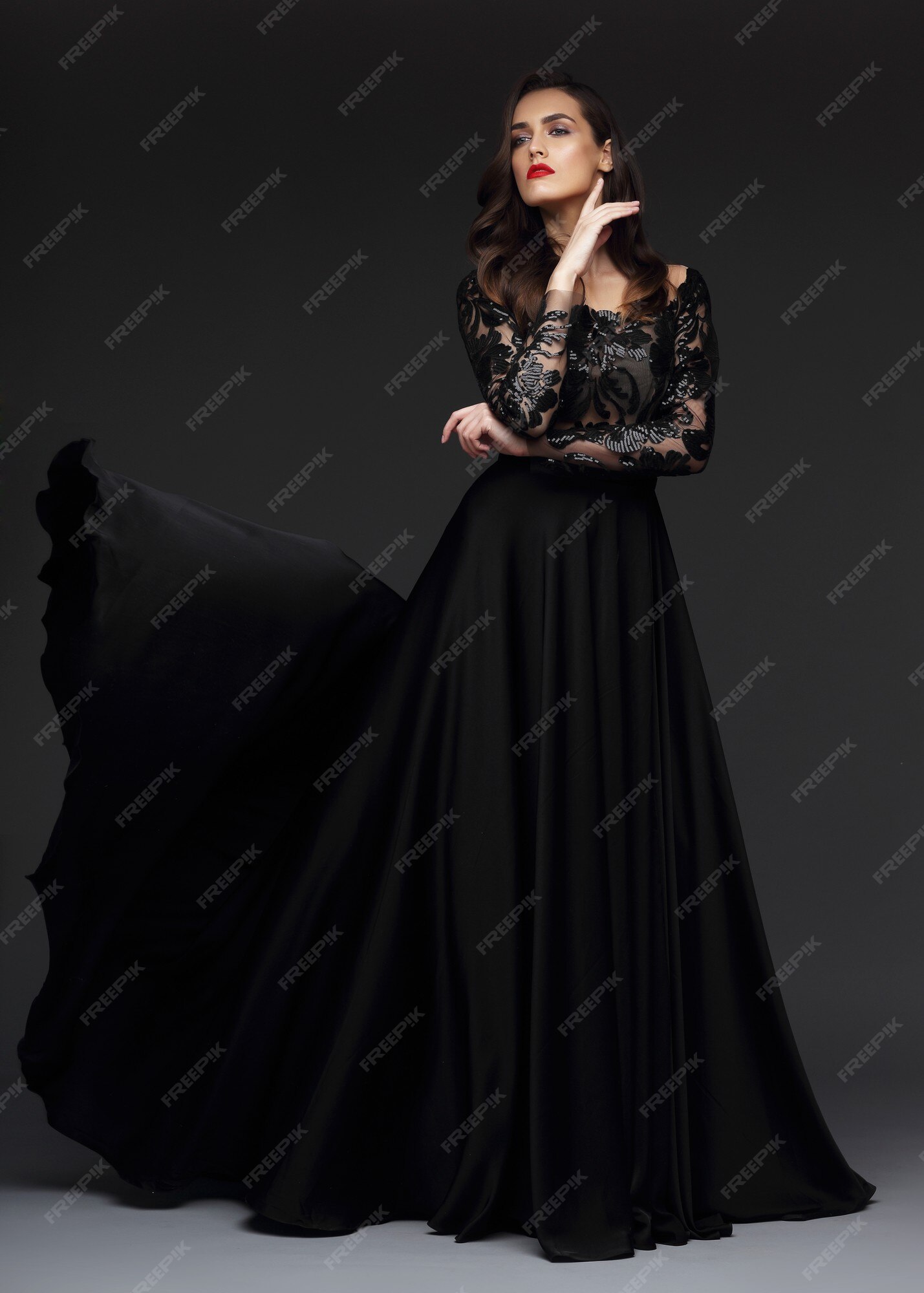 Mujer joven elegante en vestido largo negro. elegante tela voladora, vestido de noche.