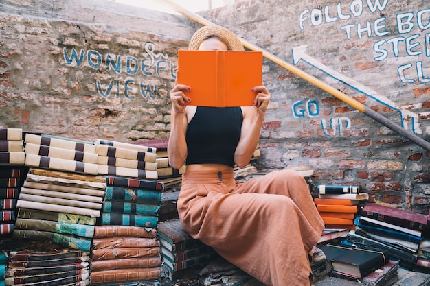 Mujer joven elegir libro en la antigua librería de segunda mano Libreria Acqua Alta en Venecia Italia