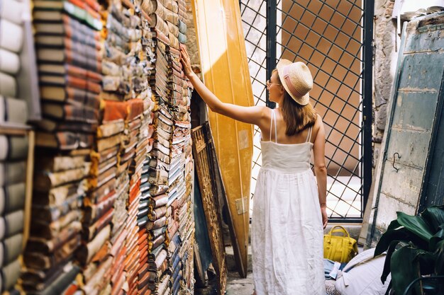 Mujer joven elegir libro en la antigua librería de segunda mano Libreria Acqua Alta en Venecia Italia