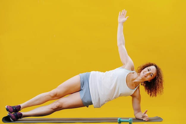 Foto mujer joven elevada de pie sobre su codo haciendo yoga