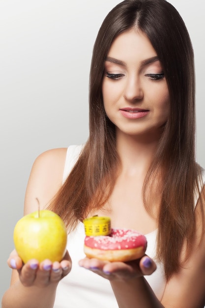 Una mujer joven elige entre alimentos saludables y nocivos