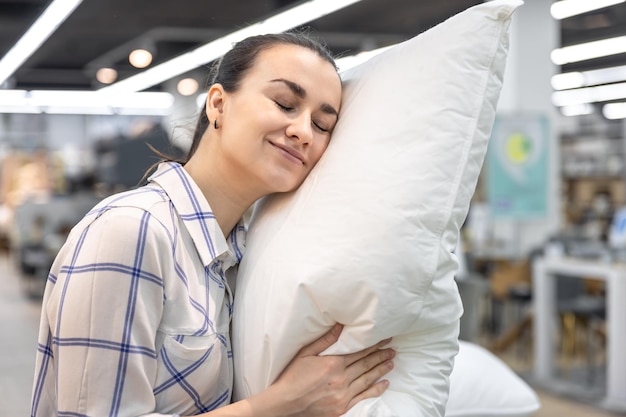 Foto una mujer joven elige una almohada en una tienda de mejoras para el hogar