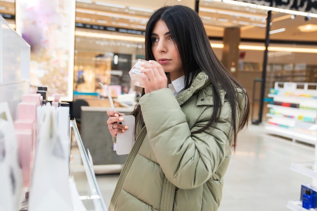 Una mujer joven elige perfume en una tiendaCompras en el centro comercial Cosméticos favoritos