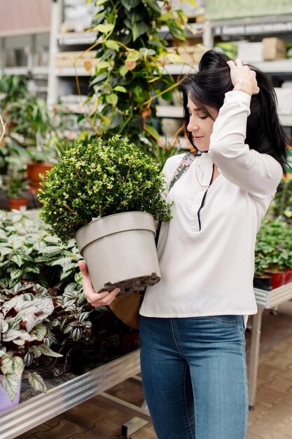 Mujer joven elige plantas de interior en una floristería