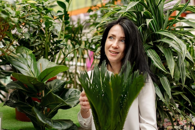 Mujer joven elige plantas de interior en una floristería