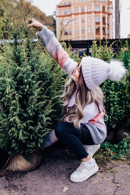 Mujer joven eligiendo un árbol de Navidad en invernadero