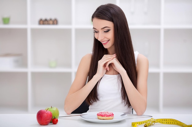 Mujer joven eligiendo entre frutas y dulces