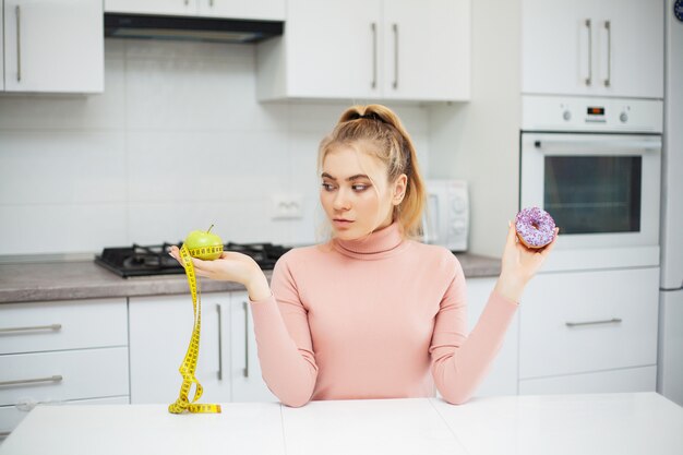 Mujer joven eligiendo entre frutas y dulces