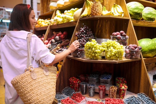 Una mujer joven eligiendo frutas en una tienda.