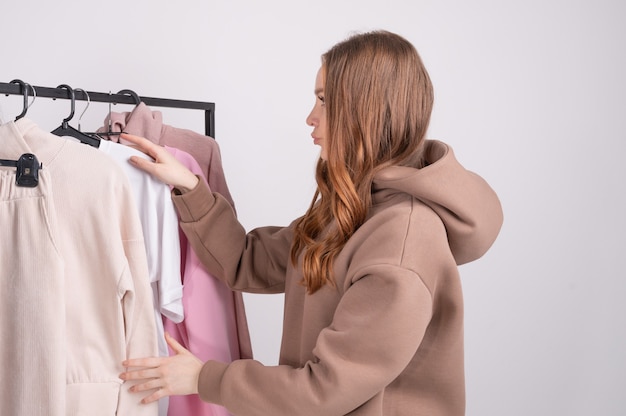 Foto mujer joven eligiendo ropa en showroom.