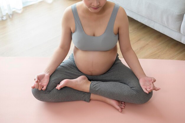 Mujer joven embarazada haciendo yoga en el concepto de cuidado de la salud y el embarazo en el hogar