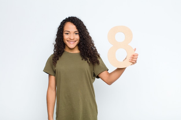 Mujer joven emocionada, feliz, alegre, sosteniendo un número 8