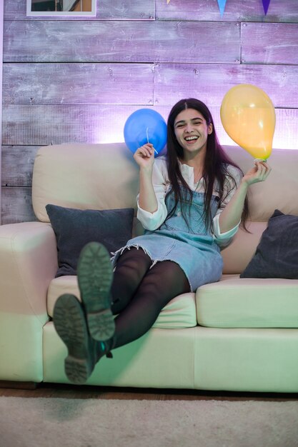 Mujer joven emocionada con globos en una gran celebración.