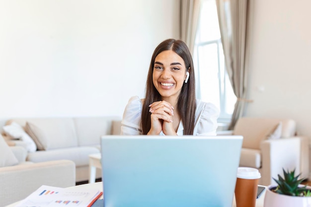 Mujer joven emocionada mirando a la cámara manteniendo una conversación divertida con colegas en línea vista de cámara web Captura de cabeza de mujer joven con auriculares riendo divirtiéndose desde la oficina en casa