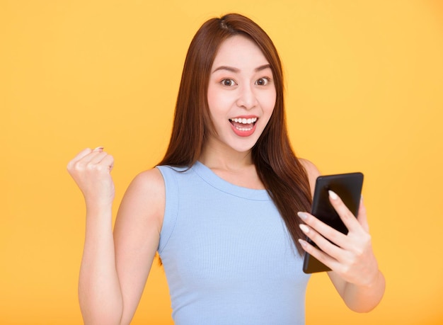 Mujer joven emocionada sosteniendo teléfono móvil y celebrando el éxito