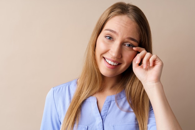 Mujer joven emocional escuchó una broma riendo hasta las lágrimas contra el fondo beige