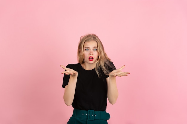 Mujer joven emocional en estudio rosa. Las emociones humanas, el concepto de expresión facial.