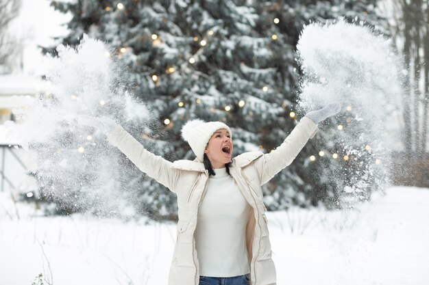 Mujer joven emocional jugando con nieve en el bosque