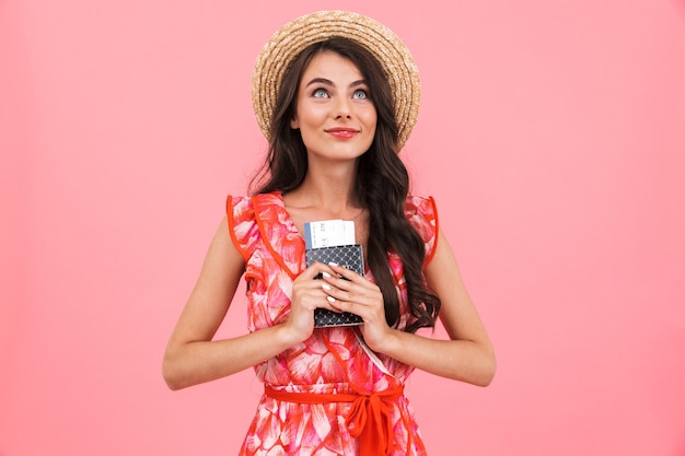 Mujer joven emocional posando pared aislada con pasaporte y boletos.