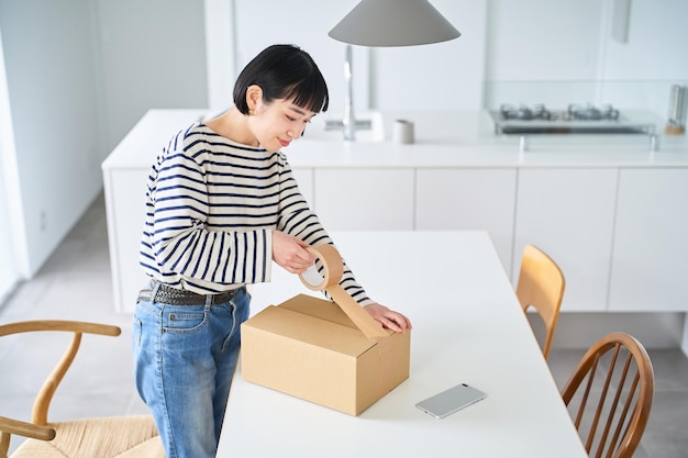 Mujer joven empacando una caja de cartón