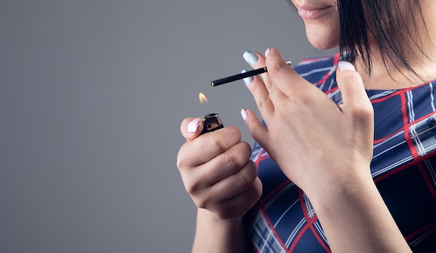 Mujer joven enciende un cigarrillo