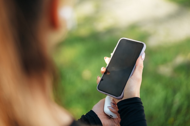 Mujer joven enciende música para correr en su teléfono inteligente al aire libre