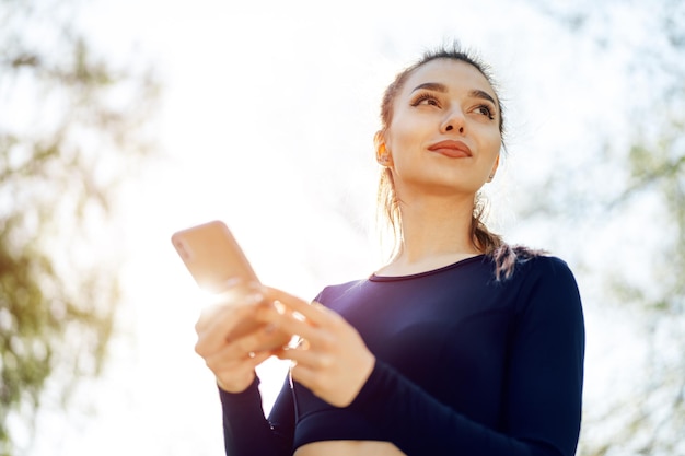 Mujer joven enciende música para correr en su teléfono inteligente al aire libre