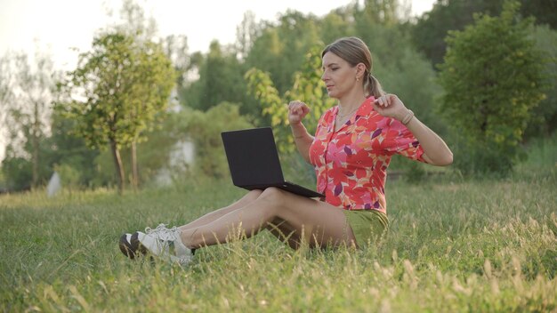 Mujer joven endereza su espalda mirando la pantalla de su computadora portátil