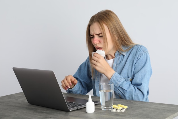 Mujer joven enferma sentada en el lugar de trabajo, concepto de frío estacional