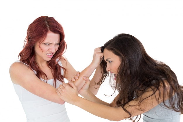 Mujer joven enojada que tira del pelo de las hembras en una lucha